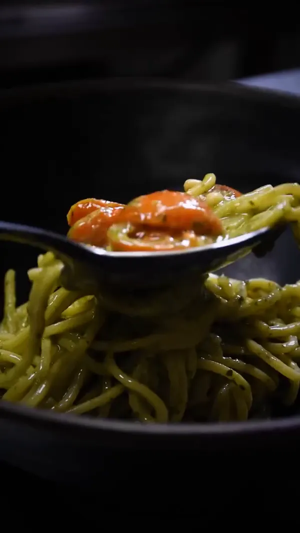Una cuchara con tomate sobre la pasta.