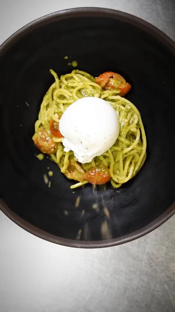 Burrata sobre pasta verde, vista desde arriba.
